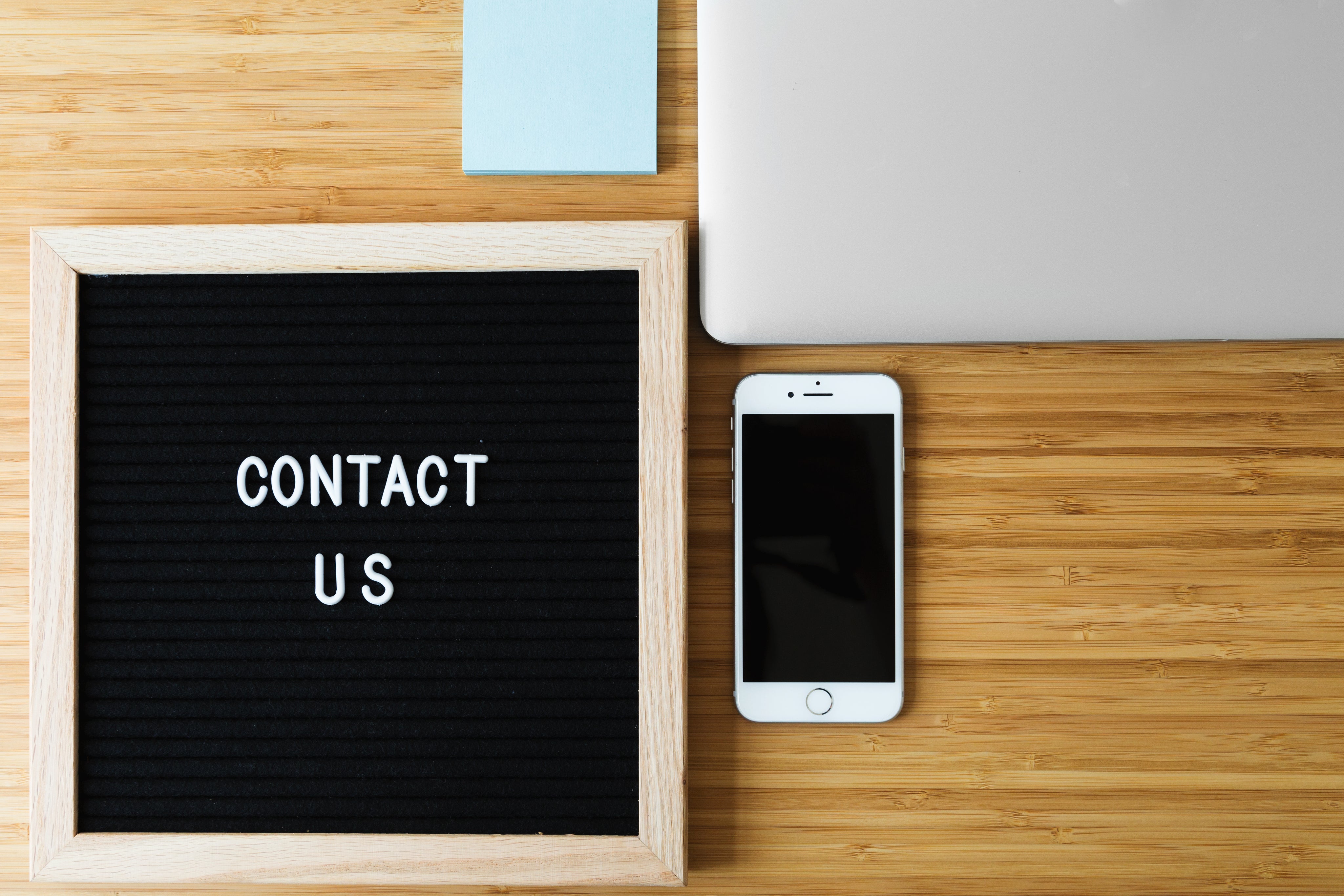 Contact us sign with phone and laptop on wooden desk for pet supplies inquiries